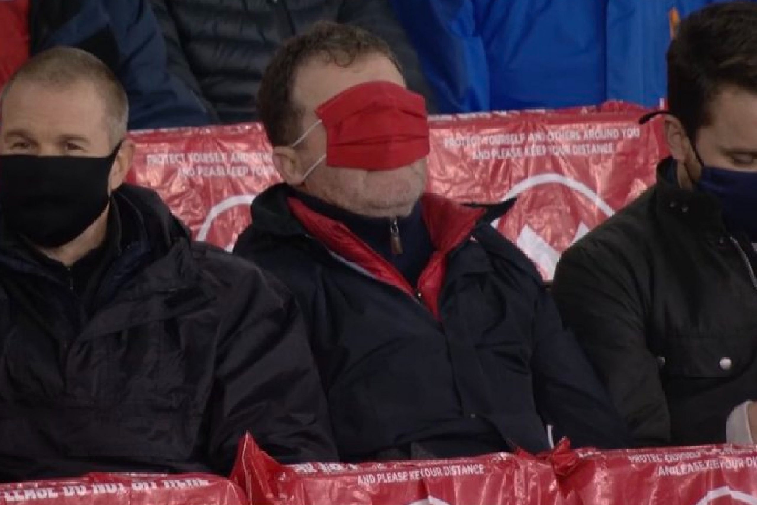 Arsenal fan covers his eyes with a face mask