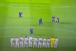 Arsenal players kneel in front of standing Slavia Prague players