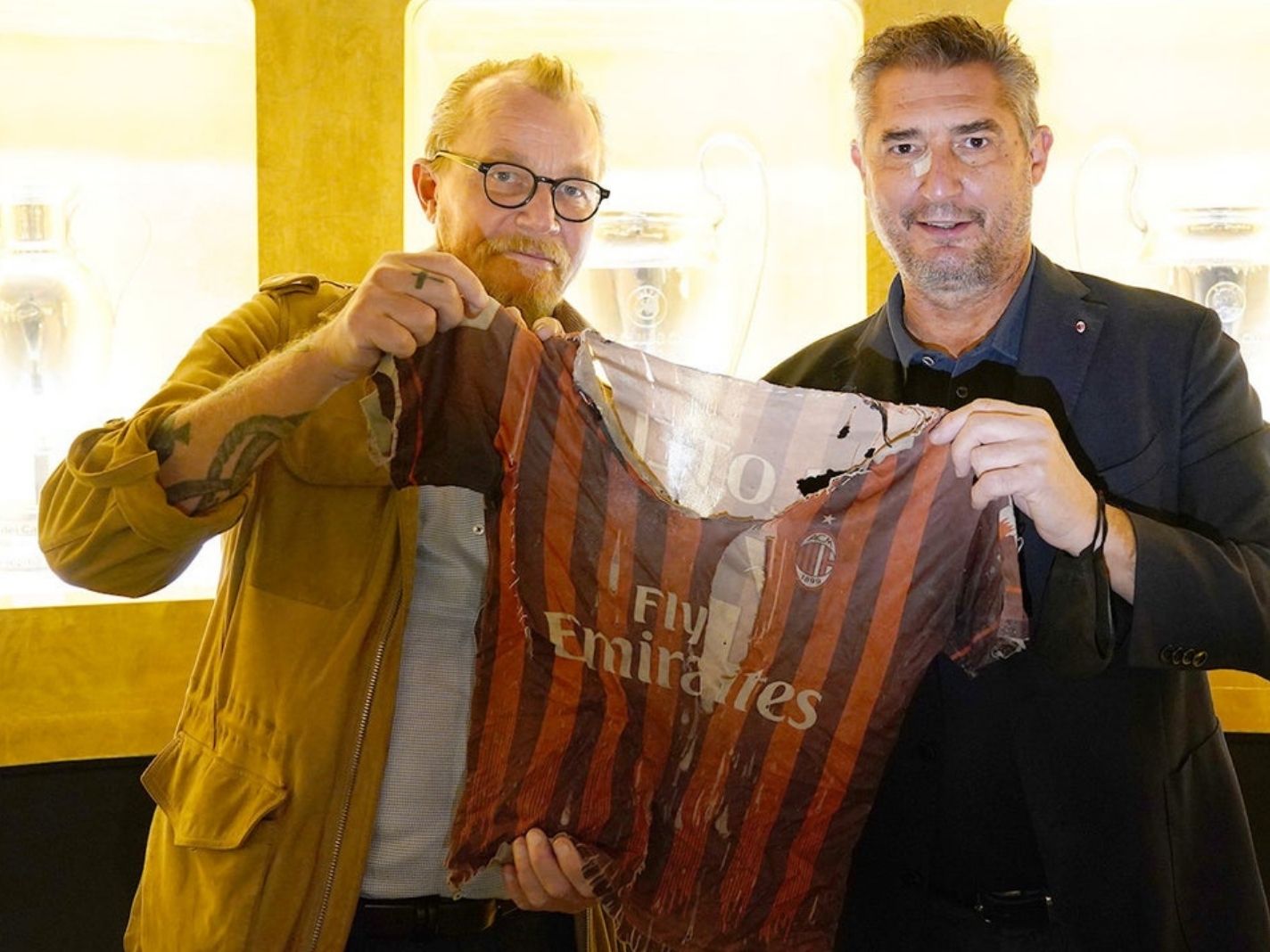 Danish war photographer Jan Grarup holds up the torn AC Milan jersey