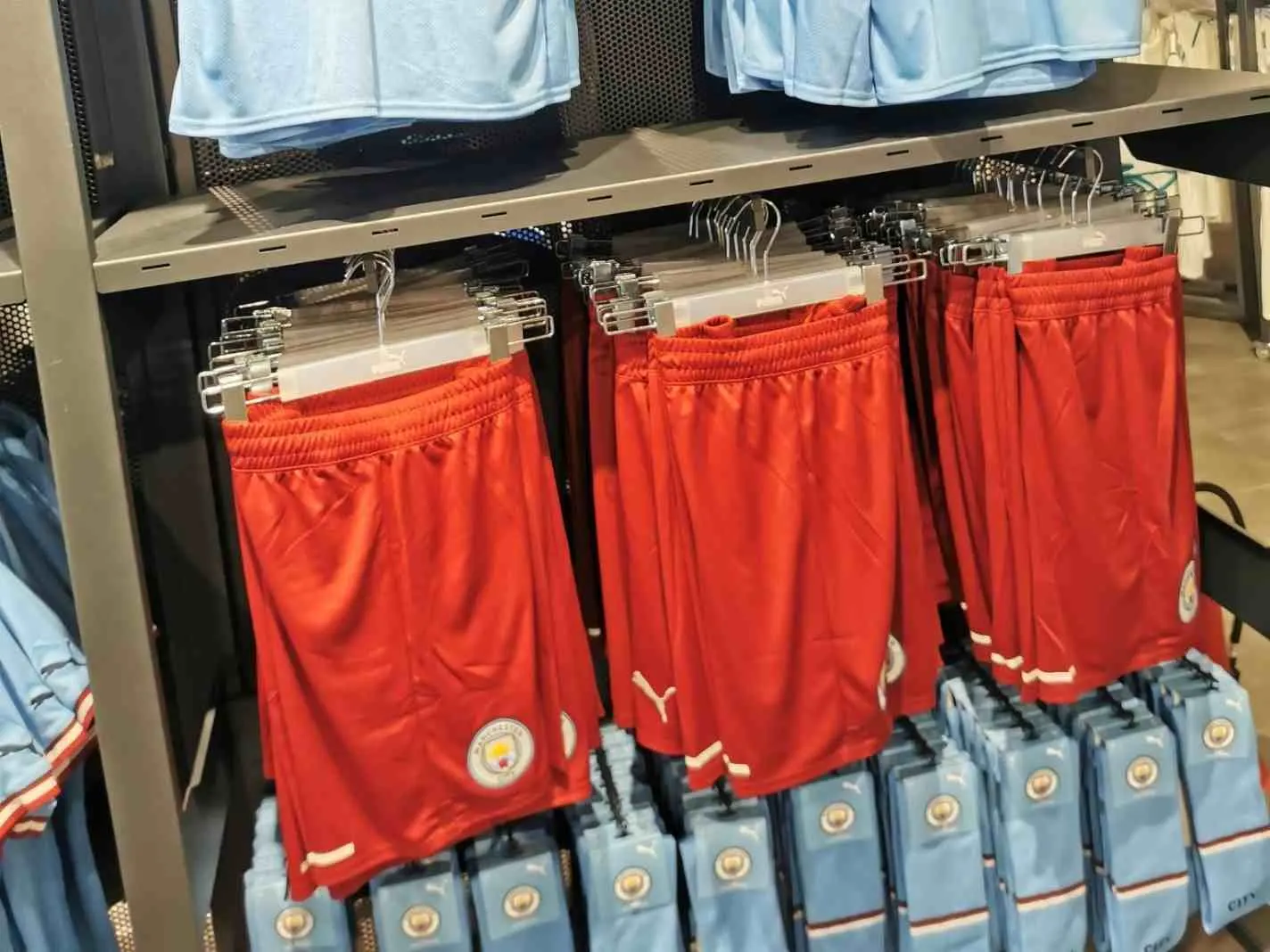 Man City home kit displayed with maroon-coloured shorts in a store